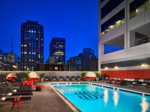 una piscina de hotel con sillas y un perfil urbano por la noche en Sonesta Philadelphia Rittenhouse Square, en Filadelfia