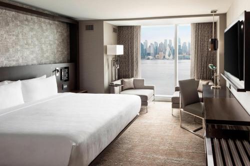 a hotel room with a large bed and a large window at Envue, Autograph Collection in Weehawken
