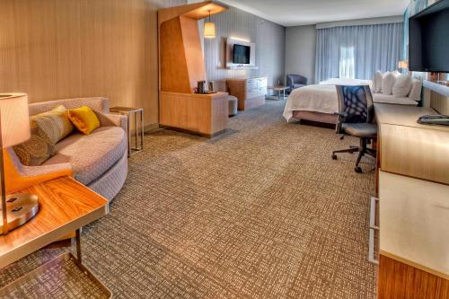 a hotel room with a bed and a couch at Courtyard by Marriott San Marcos in San Marcos