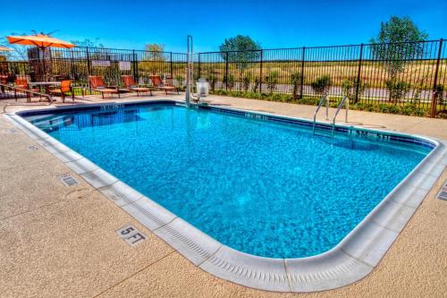 a swimming pool in a yard with chairs and an umbrella at Courtyard by Marriott San Marcos in San Marcos