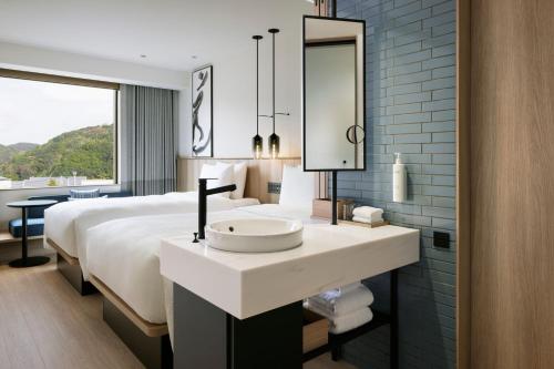 a bathroom with a sink and a bed with a mirror at Fairfield by Marriott Hyogo Awaji Fukura in Minamiawaji