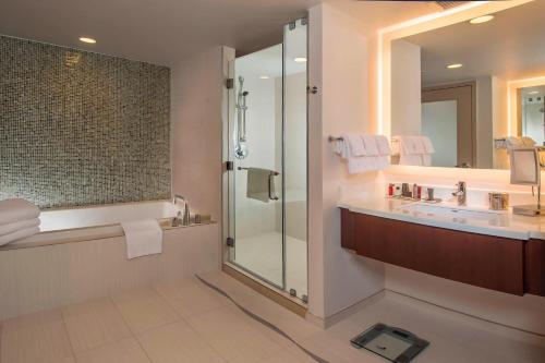 een badkamer met een douche, een wastafel en een spiegel bij Marriott Marquis Washington, DC in Washington
