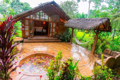 a small house with a thatched roof and a patio at Suchipakari Amazon Eco -Lodge & Jungle Reserve in Puerto Misahuallí