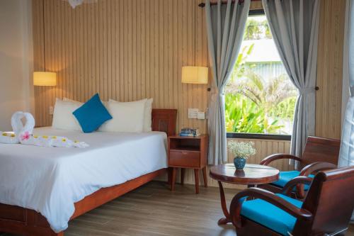 Habitación de hotel con cama, mesa y sillas en An Bang Garden Beach Homestay, en Hoi An