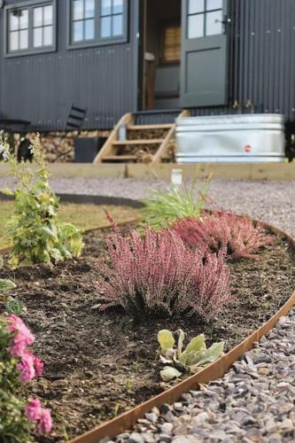 a garden with pink plants in front of a house at The Winford Retreat in Winford