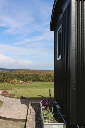 a black building with a view of a green field at The Winford Retreat in Winford