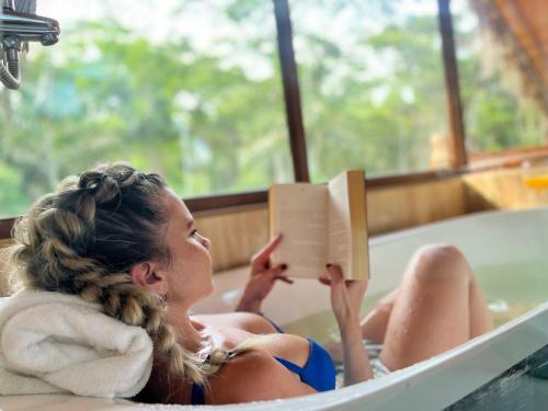 Una donna seduta in una vasca da bagno a leggere un libro di Suchipakari Amazon Eco -Lodge & Jungle Reserve a Puerto Misahuallí