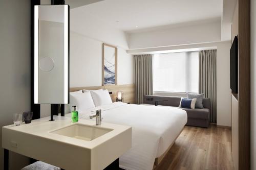 a hotel room with a white bed and a sink at Fairfield by Marriott Osaka Namba in Osaka