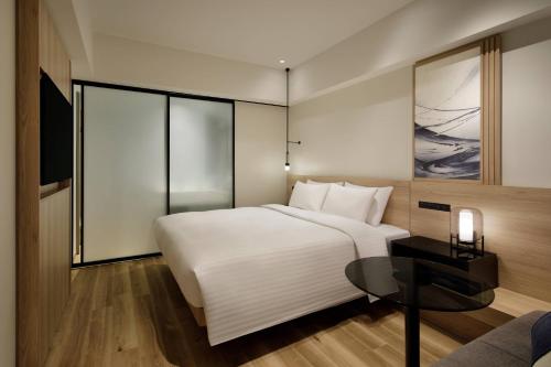 a hotel room with a white bed and a table at Fairfield by Marriott Osaka Namba in Osaka