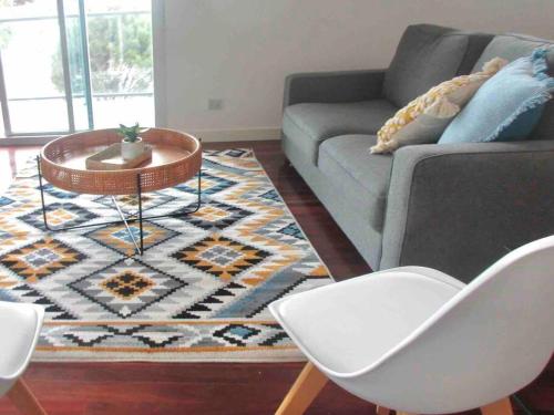 a living room with a couch and a table and chairs at Aspendale Beach Escape -Walk To Mordialloc in Aspendale