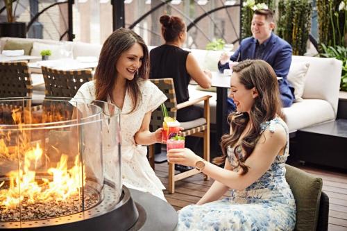 two women sitting in front of a fire pit with cocktails at The Ritz-Carlton, Toronto in Toronto