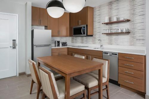 a kitchen with a wooden table with chairs and a refrigerator at Residence Inn by Marriott Rehoboth Beach in Rehoboth Beach