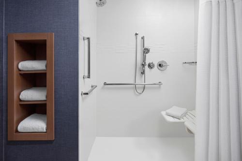 La salle de bains est pourvue d'une douche et d'un tas de serviettes. dans l'établissement Residence Inn by Marriott Rehoboth Beach, à Rehoboth Beach