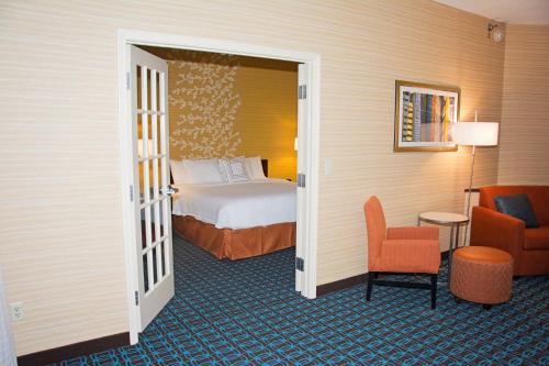 a hotel room with a bed and a chair at Fairfield Inn & Suites Butler in Butler