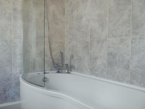 a bath tub with a faucet in a bathroom at Holly Cottage in Ystalyfera