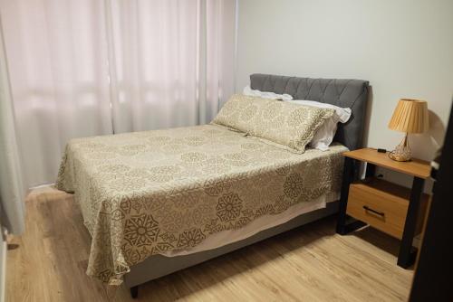 1 dormitorio con 1 cama y 1 mesa con lámpara en Fenavinho-Bento Gonçalves en Bento Gonçalves