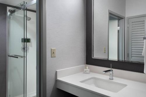 een witte badkamer met een wastafel en een spiegel bij Courtyard by Marriott Poughkeepsie in Poughkeepsie