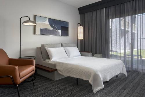 a hotel room with a bed and a chair at Courtyard by Marriott Poughkeepsie in Poughkeepsie