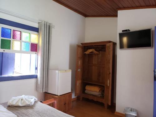 a bedroom with a bed and a tv on the wall at Hotel Ponta do Morro in Tiradentes