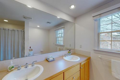 a bathroom with two sinks and a large mirror at Cotuit Mannor in Cotuit