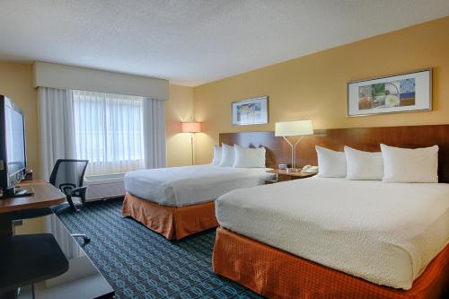 a hotel room with two beds and a flat screen tv at Fairfield Inn & Suites Jacksonville Airport in Jacksonville