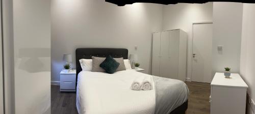 a white bedroom with a bed with towels on it at Luxury one bed apartment in Manchester city center in Manchester