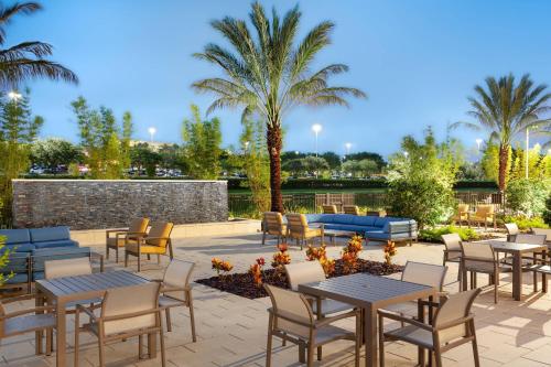 a patio with tables and chairs and palm trees at Residence Inn by Marriott Orlando at Millenia in Orlando