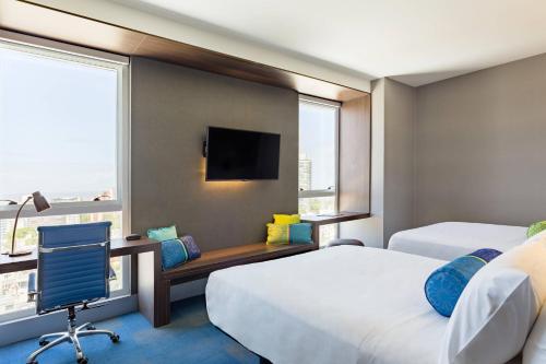 Habitación de hotel con 2 camas y escritorio con ordenador en Aloft Montevideo Hotel - Marriott International, en Montevideo