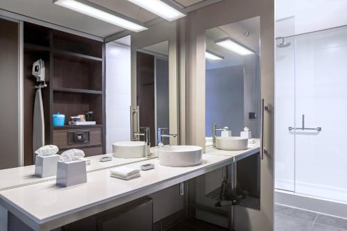 a bathroom with two sinks and two mirrors at Aloft Montevideo Hotel-Marriott International in Montevideo