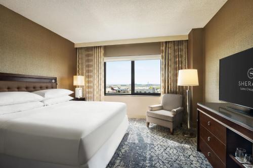 Sheraton Suites Chicago O'Hare في روزمونت: غرفه فندقيه سرير وتلفزيون