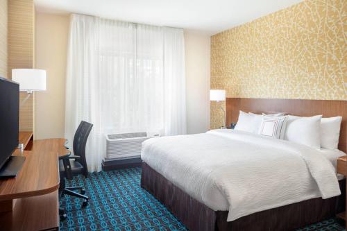 ノース・バーゲンにあるFairfield Inn & Suites by Marriott North Bergenのベッド、デスク、窓が備わるホテルルームです。
