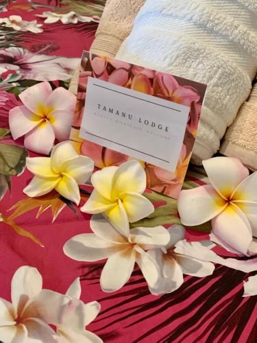 a sign sitting on top of a bed with flowers at TAMANU LODGE in Punaauia