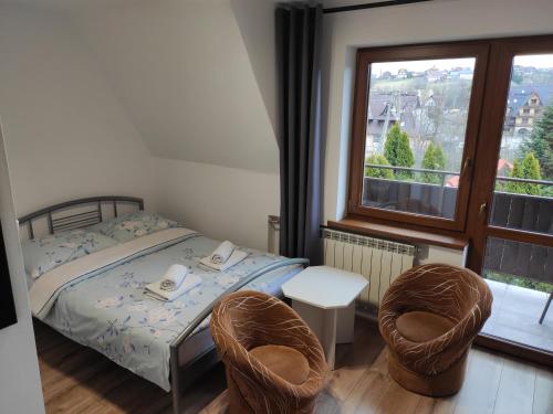 - une chambre avec un lit, deux chaises et une fenêtre dans l'établissement Willa Ewelinka, à Zakopane