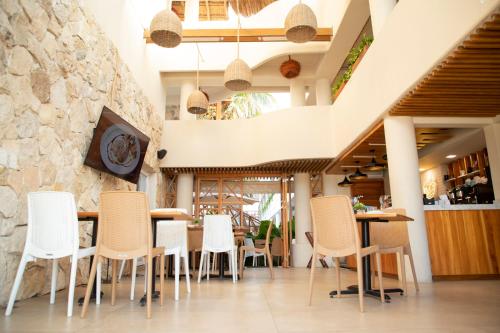 una sala da pranzo con sedie bianche e un muro in pietra di Casa Viento Hotel a Ciudad del Carmen