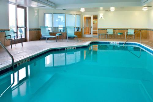 - une piscine avec des chaises et des chaises bleues dans un bâtiment dans l'établissement SpringHill Suites by Marriott Syracuse Carrier Circle, à East Syracuse