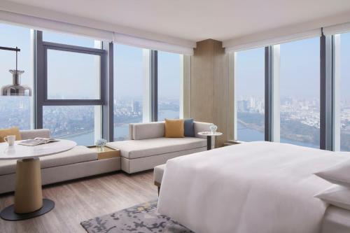 Jinhua Marriott Hotel في Jinhua: غرفة نوم بسرير ابيض كبير واريكة