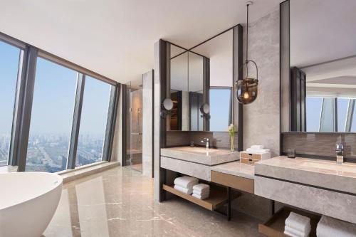 Jinhua Marriott Hotel في Jinhua: حمام به مغسلتين وحوض استحمام ومرآة