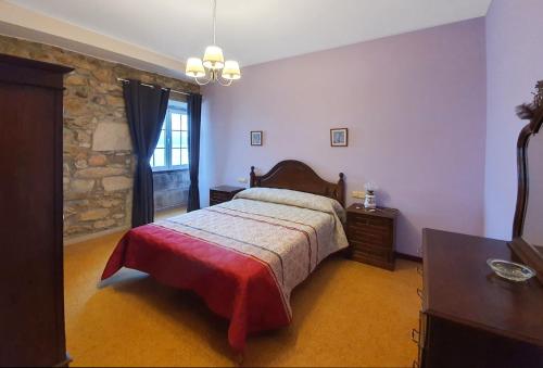 1 dormitorio con cama y pared de piedra en La Casa de Ana en Fisterra, en Finisterre