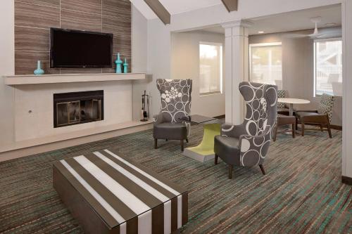a living room with a fireplace and chairs and a tv at Residence Inn Ontario Airport in Ontario