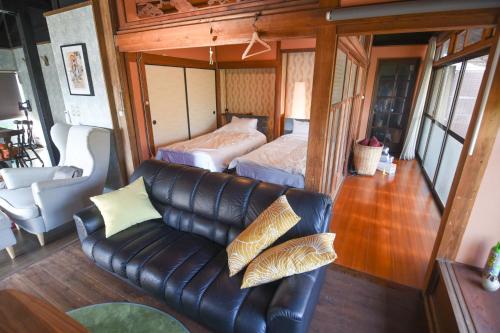 sala de estar con sofá de cuero y cama en 山鹿師蔵, en Yamaga