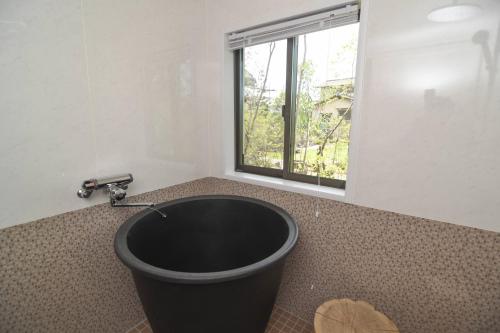 baño con bañera negra y ventana en 山鹿師蔵 en Yamaga