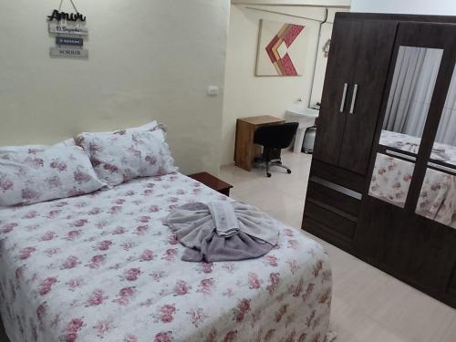 ein Schlafzimmer mit einem Bett und einer Kommode mit einem Hemd drauf in der Unterkunft Estúdio Mobiliado em Poços in Poços de Caldas