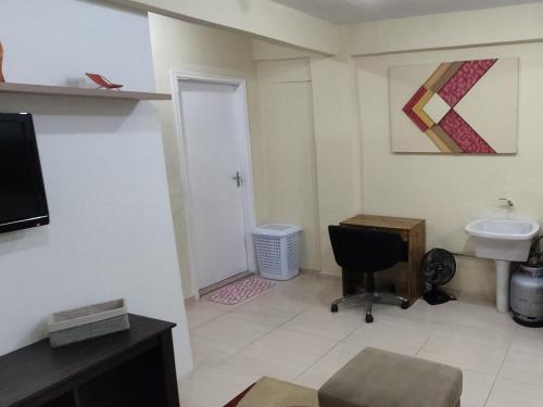 a bathroom with a sink and a desk with a chair at Estúdio Mobiliado em Poços in Poços de Caldas