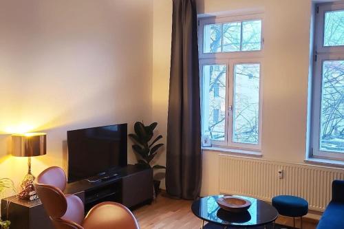 a living room with a flat screen tv and two windows at Design Altbauwohnung mit Balkon und Parkplatz in Leipzig