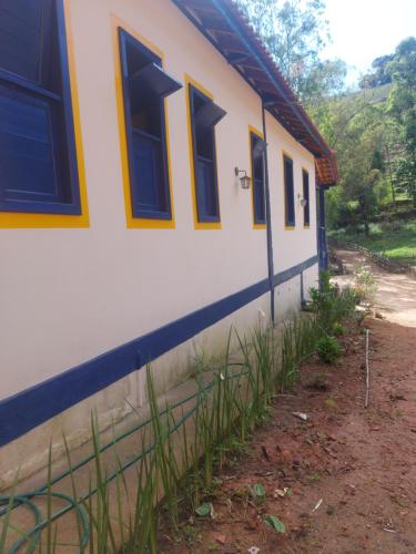 einen seitlichen Blick auf ein Haus mit blauen Fenstern in der Unterkunft Fazenda do Quartel in Manhumirim