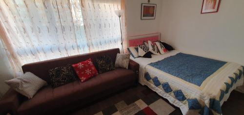 a bedroom with a bed and a couch with pillows at KFOT Cosy STUDIO FLAt, STOCKWELL in London