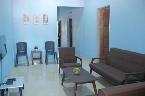 uma sala de estar com cadeiras, um sofá e uma mesa em Mufeed Homestay em Kampong Wakaf Tengah