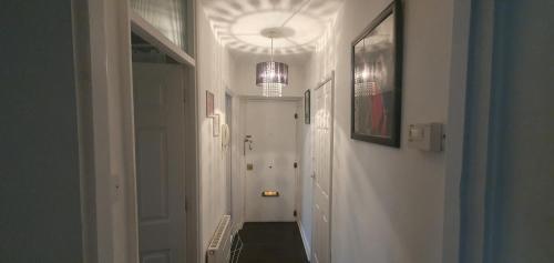 a hallway with a white hallway with a chandelier at KFOT Cosy STUDIO FLAt, STOCKWELL in London