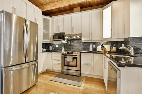 a kitchen with white cabinets and a stainless steel refrigerator at STUNNING full APARTMENTS - stocked KITCHENS - WASHER & DRYERS - WORKSPACE PROVIDED - FAST WIFI - LOCATED on the FAMOUS ST Denis street - Near METRO MONT ROYAL in Montréal