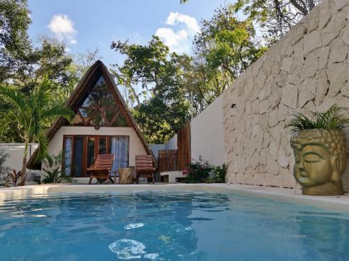 a villa with a swimming pool in front of a house at Tzunum Jade in Tulum